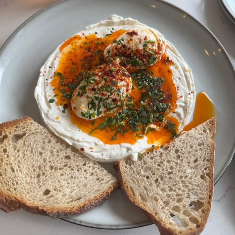 Fora Cafe's poached eggs with chili oil and herbs on a bed of yogurt, served with toast.
